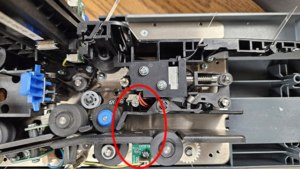 A scanner with the cover removed and the location of the double-feed sensor circled near the feeder.