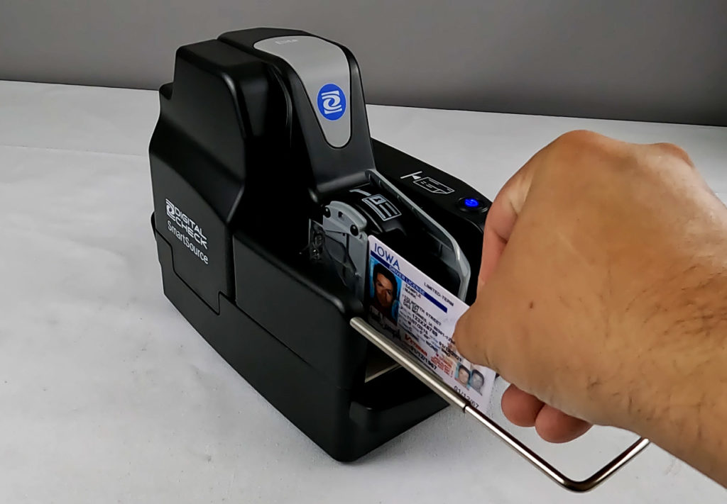 a hand feeding an ID card into a scanner.