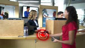 woman handing a glowing ID card to a bank teller.